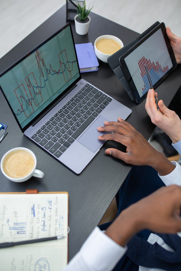 Business professionals analyzing data on a laptop and tablet in a modern office.